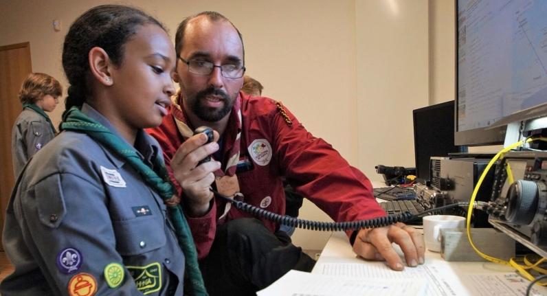 photo: adult leader showing Scout how to use amateur radio