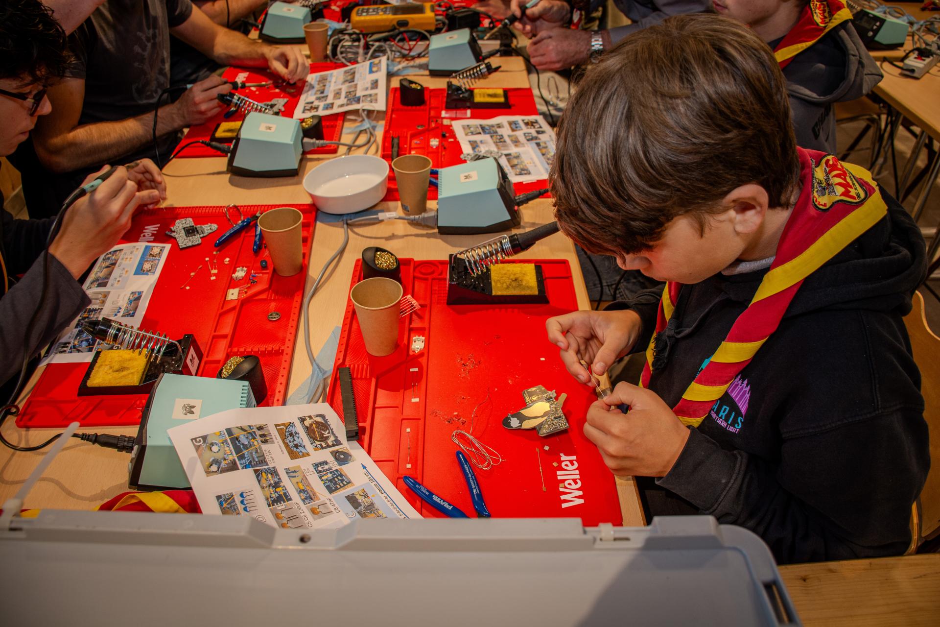 Young Scout learning to solder during JOTA-JOTI.